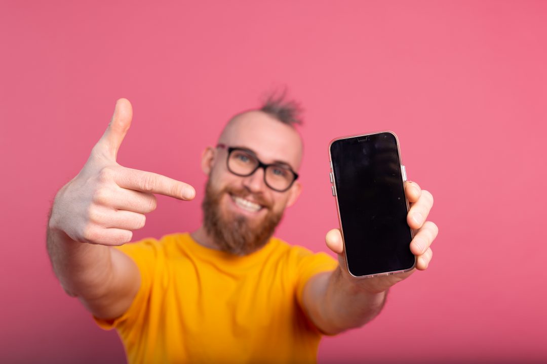 Hombre contento enseña la pantalla del móvil
